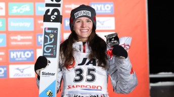 Abigail Strate montre sa médaille d'argent en posant pour une photo avec sa paire de ski