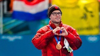 Laurent Dubreuil avec une médaille de bronze autour du cou fait un signe en forme de coeur avec ses mains.