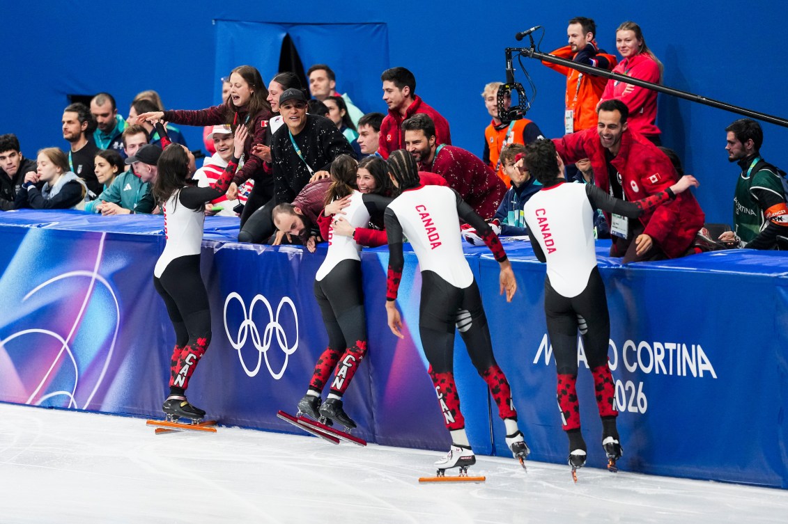 Les patineurs du relais mixte célèbrent en compagnie des autres membres de l'équipe canadienne.