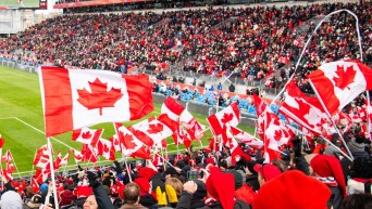 Les partisans du Canada agitent des drapeaux canadiens dans les estrades du BMO Field de Toronto.